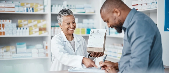 A pharmacy assistant serving a customer at the counter